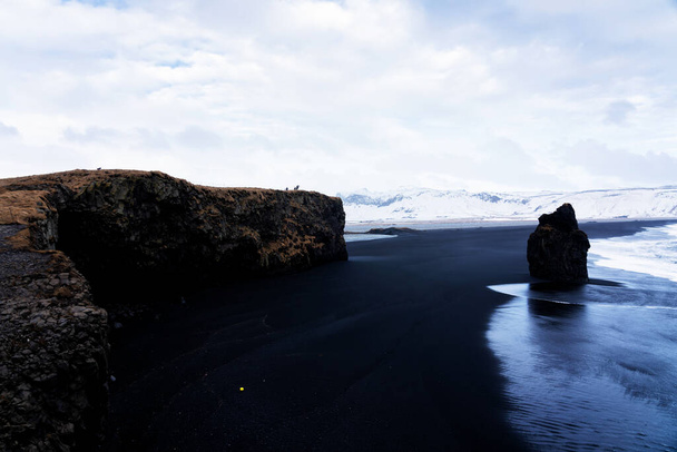 Η μαύρη αμμουδιά του Reynisfjara και το βουνό Reynisfjall από το ακρωτήριο Dyrholaey στη νότια ακτή της Ισλανδίας. - Φωτογραφία, εικόνα