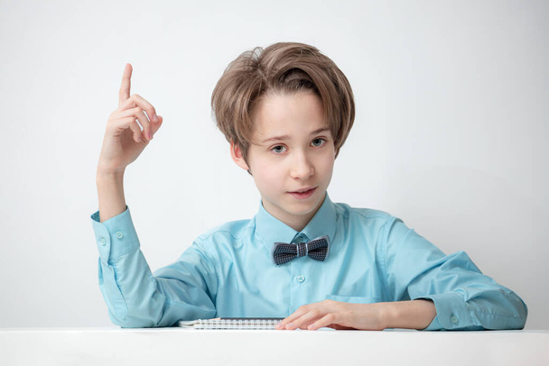 portrait of smart boy in a blue shirt with a bow tie, teenager shows thumb up, concept of interesting idea, academic success, attentive intelligent look - Фото, изображение