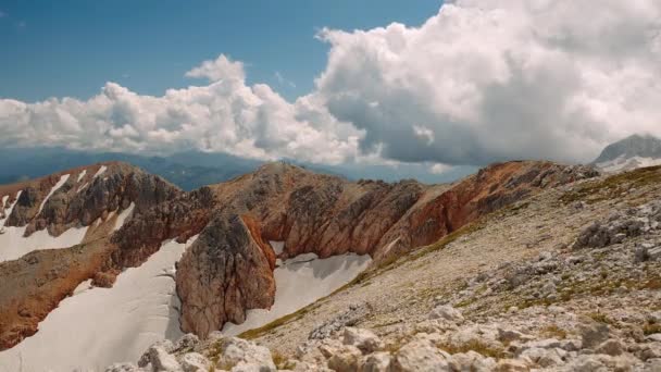 Wunderbarer Blick auf braune und graue Schneeberge im Kaukasus unter großen fliegenden Wolken im Sommer, Blick vom Hang aus von Steinen in Adygea, Russland. Konzept des aktiven Wanderns und Tourismus in den Bergen. - Filmmaterial, Video