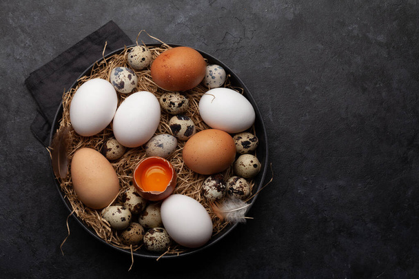 White, brown and quail eggs on stone background. Top view with copy space. Flat lay - Photo, Image