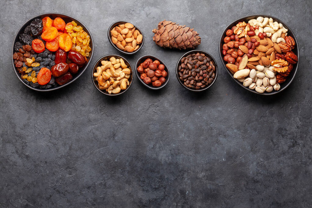 Různé sušené ovoce a ořechy na tmavém kamenném stole. Horní pohled plochý ležel s kopírovacím prostorem - Fotografie, Obrázek