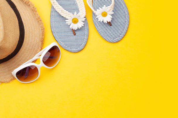 Summer vacation items and accessories. Flip flops, sunglasses and sun hat on yellow background. Top view flat lay with copy space - Photo, Image