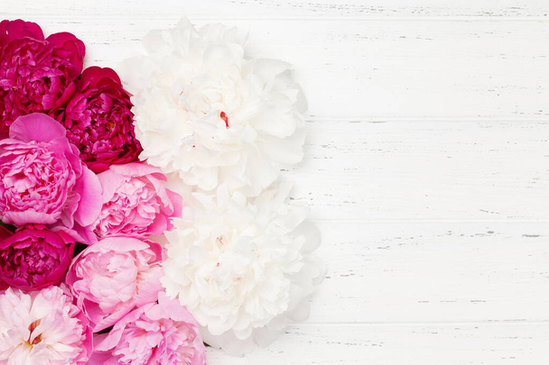 Πολύχρωμα ροζ, λευκά και μοβ παιώνια λουλούδια σε ξύλινο τραπέζι. Κάτοψη με χώρο αντιγραφής. Επίπεδη - Φωτογραφία, εικόνα