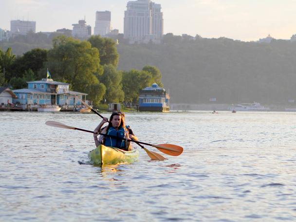 Water sports of people on the Dnipro River in Kiev, Ukraine who ride a boat on the background of the city - Photo, Image