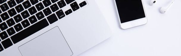Kulaklıklı ve akıllı telefonlu yeni modern dizüstü bilgisayar klavyesi beyaz arkaplanda izole edilmiş, yakın görünüm  - Fotoğraf, Görsel