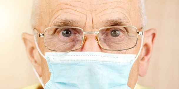 aged pensioner in glasses and blue disposable face mask - Fotó, kép