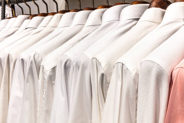 Ein Haufen Kleiderbügel mit Männerhemden. Kleiderladen im Einkaufszentrum. Hemden stapelweise an Regal hängen, Nahaufnahme. - Foto, Bild