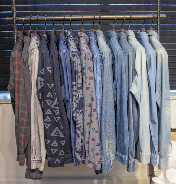Ein Haufen Kleiderbügel mit Männerhemden. Kleiderladen im Einkaufszentrum. Herrenhemd hängt im Laden zum Verkauf. - Foto, Bild