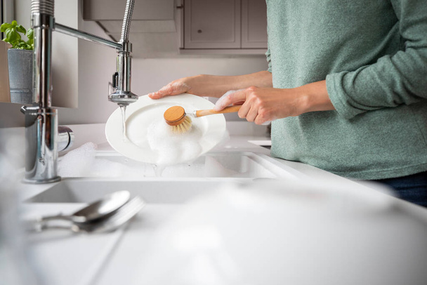 Woman Washing Up At Home Using Eco Dish Brush For Sustainable Lifestyle - Valokuva, kuva