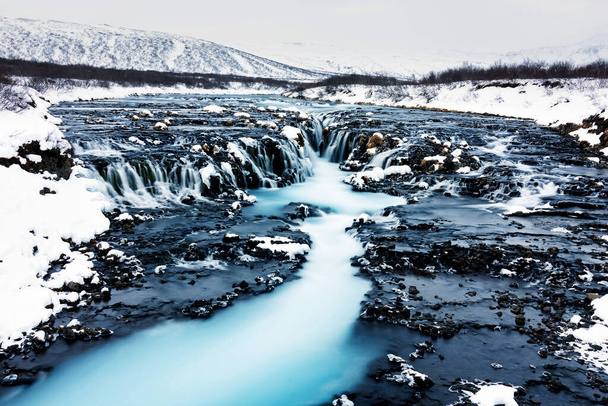 Vista incrível da cachoeira Bruarfoss no inverno. A água azul flui sobre pedras. Sol da meia-noite da Islândia. Visite a Islândia. Mundo da beleza
. - Foto, Imagem