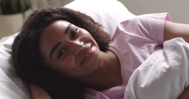 Afrikaans amerikaans meisje glimlachen op camera, liggend in bed - Video