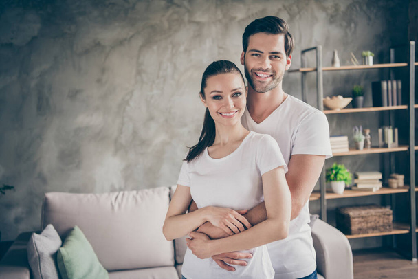 Photo of pretty charming lady handsome guy couple relaxing stand close stay home good mood quarantine hugging spend time together toothy smiling living room indoors - 写真・画像