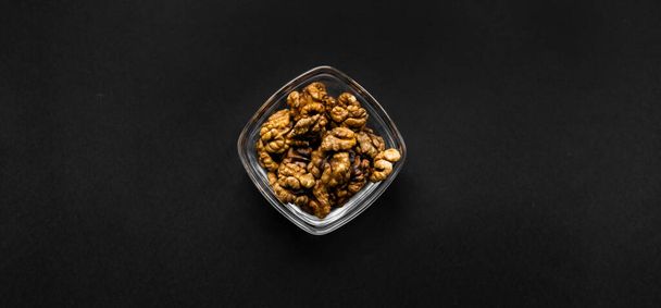 Walnut in a small plate on a black table. Walnuts is a healthy vegetarian protein nutritious food. Natural nuts snacks. - Foto, imagen
