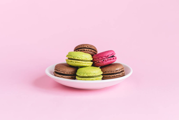 Ein Set schmackhafter französischer Makronen auf rosa Hintergrund. Rosa, grüne und braune Makronen. Platz für Text. - Foto, Bild