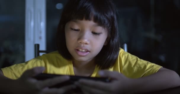 Asian kid, Thai girl play phone at night after dinner on table - Footage, Video