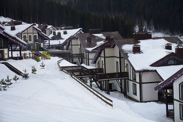 Wooden houses in the snow winter holiday. Ski resort, cottage town. - Photo, Image