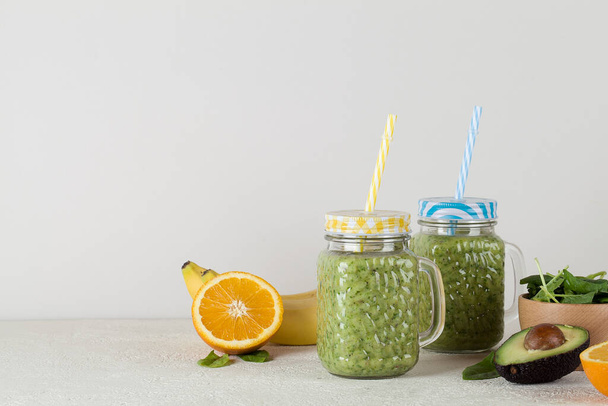 Зеленый смузи на сером фоне с авокадо, шпинатом, бананом, апельсином. концепция здорового питания. копировальное пространство
 - Фото, изображение
