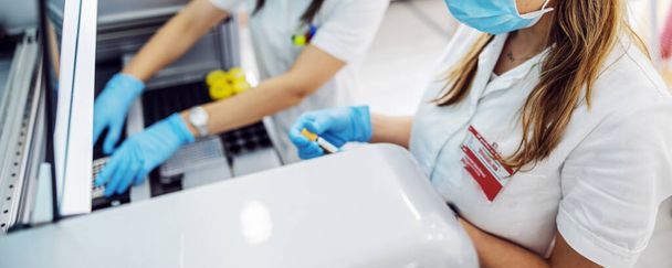 Laboratorní asistenti vkládání zkumavky s krevními vzorky do stroje při stání v laboratoři. - Fotografie, Obrázek