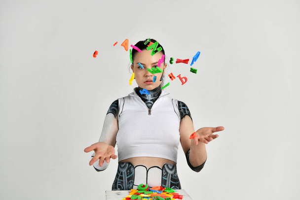piękna dziewczyna w stroju robota bawi się kolorowymi literami i uczy się praw grawitacji - Zdjęcie, obraz