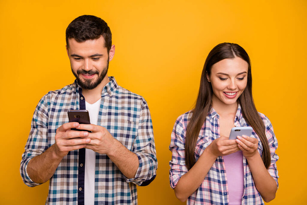 Photo attractive lady handsome cheerful guy couple look telephone screen addicted users popular bloggers wear casual plaid shirts outfit isolated yellow color background - Foto, afbeelding