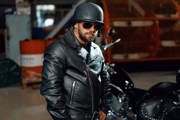 Ritratto di uomo barbuto motociclista in occhiali da sole scuri su sfondo scuro - Foto, immagini