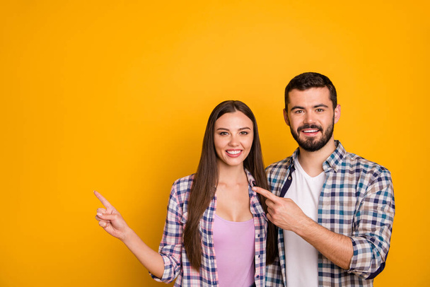 Portrait of positive cheerful team promoter woman man point index finger copyspace indicate ads promo direct way wear checkered plaid shirt isolated over bright shine color background - Foto, Imagen