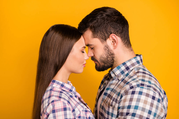 Closeup profile photo pretty lady handsome guy tenderness eyes closed leaning heads with love emotions stand close wear casual plaid shirts isolated yellow color background - Фото, изображение
