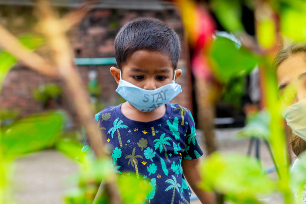 Retrato de um menino vestindo uma máscara médica e viajando no jardim. Proteger da infecção pelo coronavírus em quarentena domiciliar
. - Foto, Imagem