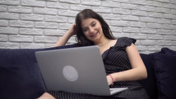 Mujer atractiva viendo en la pantalla del ordenador portátil lanzando películas de cine relajante en casa - Imágenes, Vídeo