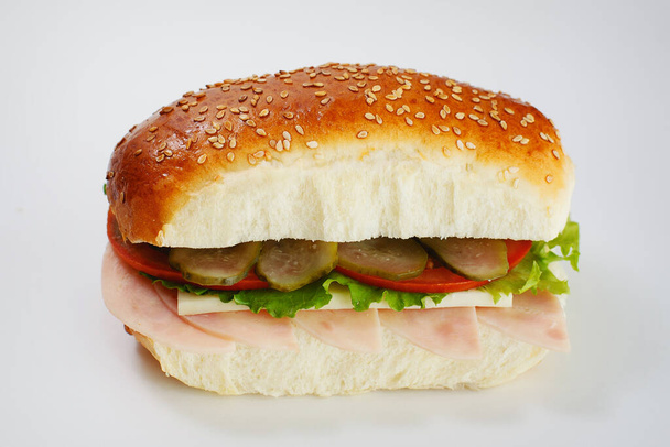 Sappige sandwich met komkommers, sla, kaas en ham op een witte achtergrond. Hoge kwaliteit foto - Foto, afbeelding