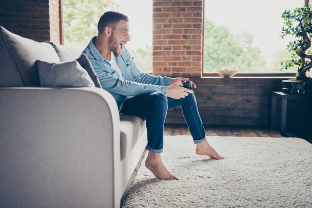 Profile photo of domestic handsome guy relaxing stay home quarantine time playing video games playstation football final match sit cozy sofa modern interior living room indoors - Fotografie, Obrázek
