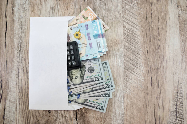 Taschenrechner, Griwna und Dollar in einem Umschlag. Kopie des Raumes. Platz für Text. Blick von oben. - Foto, Bild