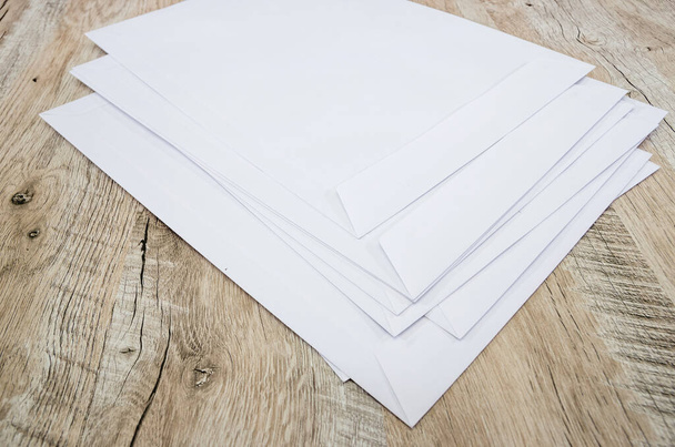 white envelopes on a wooden background. A lot of envelopes. - Photo, Image