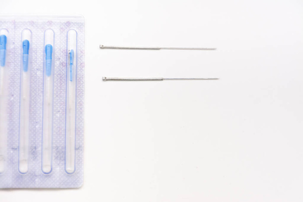 Two acupuncture needles next to a package with needles on a white table with copy space - Photo, Image