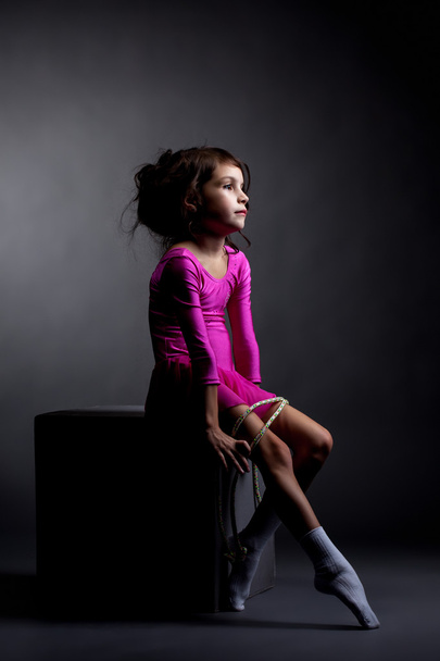 Sad artistic gymnast sitting on cube with rope - Foto, immagini