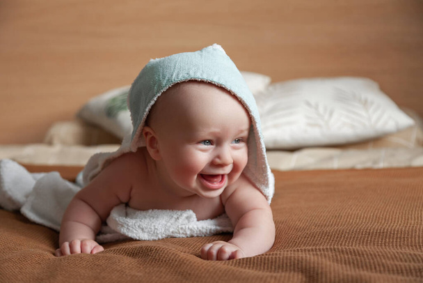  Küçük bebek beyaz havluya sarılıp yatağa uzanıyor. - Fotoğraf, Görsel