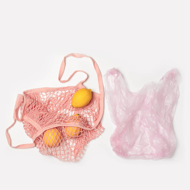 プラスチック製のバッグとピンクの綿メッシュバッグ環境に優しい。比較の概念。プラスチックなしでは廃棄物はゼロ。コピースペース付きライトグレーの背景。果物だレモン。誰も. - 写真・画像