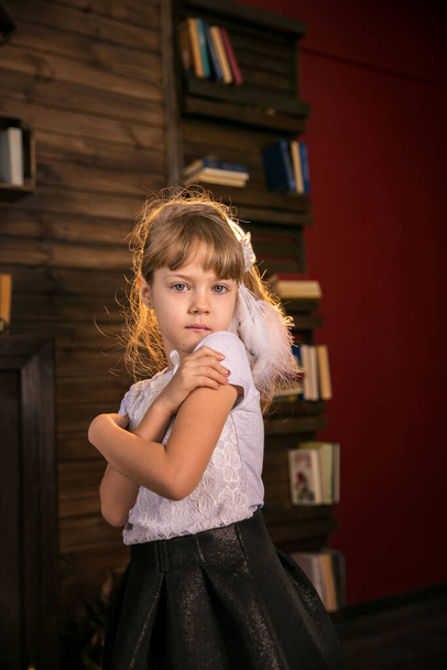 Portrait of a little beautiful girl in the library against the background of books - Fotografie, Obrázek