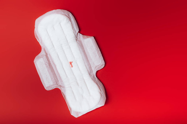 sanitary napkin with red balls imitating menstruation on a red background, health care, monthly protection, reliable friend. - Photo, Image