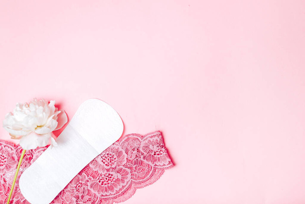 sanitary napkin with a beautiful peony and underwear on a pink background, health care, monthly protection, reliable friend. - Φωτογραφία, εικόνα