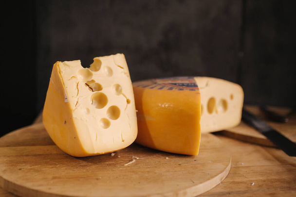 Cheese maasdam om wooden board with knife for cheese - Foto, Imagen
