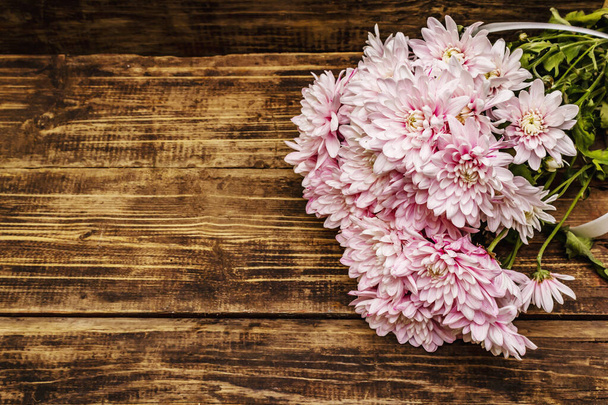 Bouquet de chrysanthèmes délicatement roses. Beau cadeau sur fond bois vintage. Concept d'humeur romantique, vue de dessus - Photo, image