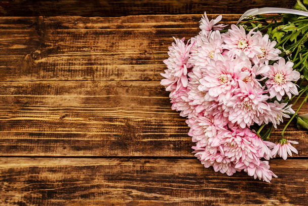 Profumo di crisantemi delicatamente rosa. Bellissimo regalo su sfondo vintage in legno. Concetto di umore romantico, vista dall'alto - Foto, immagini