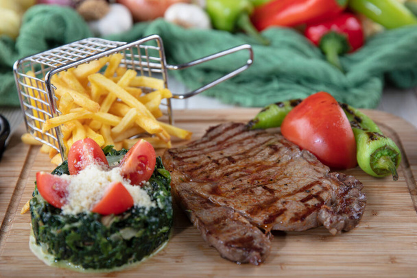 Marha steak paprikaszósszal és grillezett zöldségek vágódeszkán fa alapon. - Fotó, kép