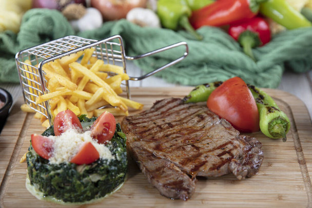 Beef steak with pepper sauce and Grilled vegetables on cutting board on wooden background. - Photo, Image