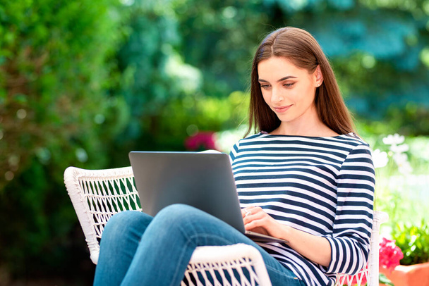 Shot of beautiful young woman using her laptop while sitting in the garden and while working at home.  - Fotoğraf, Görsel