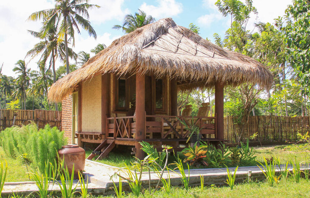 Sasak μπαμπού σπίτι και κήπο στο Lombok θέρετρο, Ινδονησία. Kuta Lombok είναι ένα εξωτικό παράδεισο στο νησί της Ινδονησίας, με όμορφες παραλίες λευκή άμμο και κρυστάλλινα γαλαζοπράσινα νερά. - Φωτογραφία, εικόνα