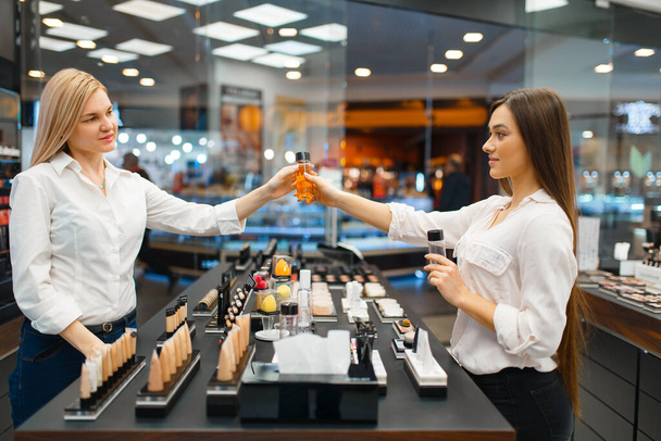 Cosmetician at the counter and woman in cosmetics store. Luxury beauty shop salon, female customer and beautician in fashion store - Foto, immagini