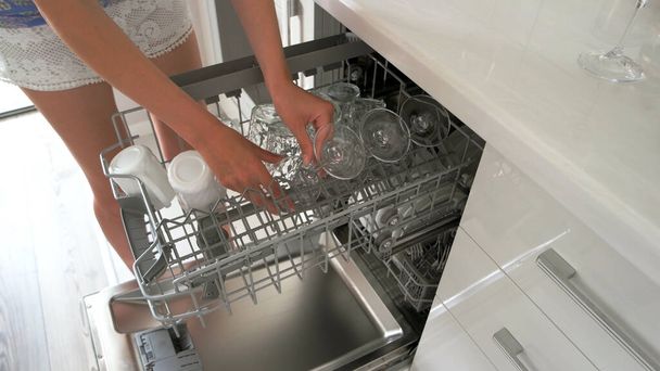 Kobieta zmywa naczynia w zmywarce. - Zdjęcie, obraz