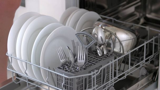 Zárja be a nyitott mosogatógép tiszta tányérokkal és evőeszközökkel. - Fotó, kép